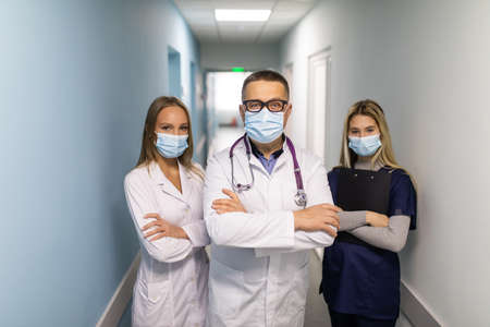 Group of doctors with face medical masks looking at camera, corona virus concept.の写真素材