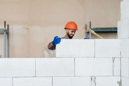 bricklayer builder working with autoclaved aerated concrete blocks. Walling, installing bricks on construction siteの写真素材