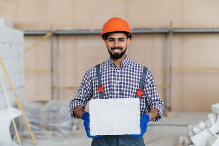 The builder holds autoclaved aerated bricks. The concept proposes to use autoclaved aerated bricks in the construction of houses.の写真素材