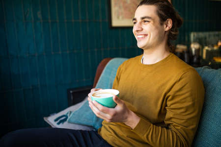 Young man drinking a cup of coffee in the cafe