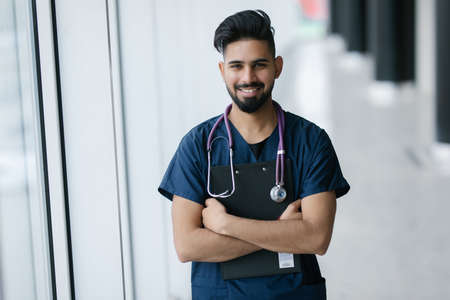 medicine, healthcare and people concept - happy male doctor with stethoscope and clipboard at clinicの写真素材