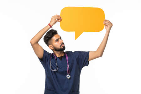 Indian doctor man standing and holding yellow speech bubble over white backgroundの写真素材