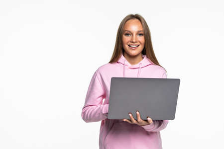 Young happy smiling woman in casual clothes holding laptop and sending email to her best friendの写真素材