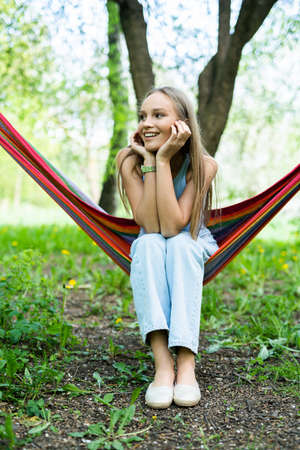 Beautiful dreamy woman sitting in a hammock outdoorsの写真素材