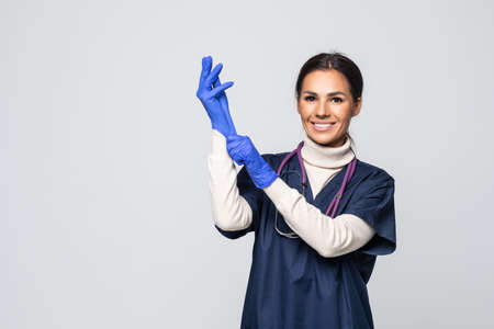 Beautiful female doctor or nurse wearing protective mask and latex or rubber gloves on gray backgroundの写真素材