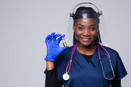 Coronavirus vaccine and syringe in hands of african american doctor isolated on white backgroundの写真素材