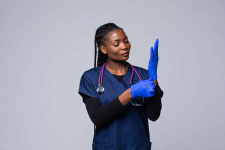 African american nurse or doctor woman wearing medical face mask wearing disposable gloves isolated white backgroundの写真素材