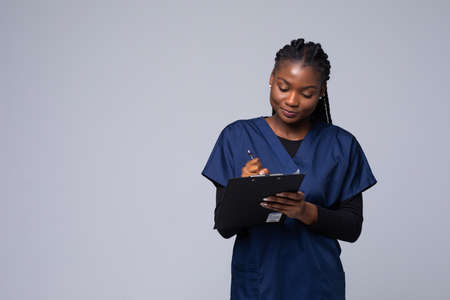 Young African American nurse holding a clipboard isolated on white backgroundの写真素材