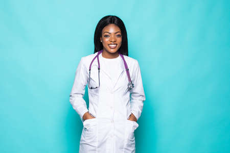 Portrait of beautiful African American doctor or nurse with arms crossed over turquoise background