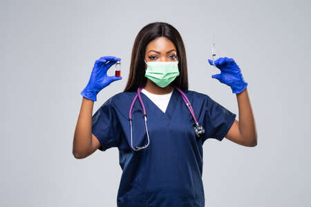 Vaccine and syringe in hands of african american doctor isolated on whiteの写真素材