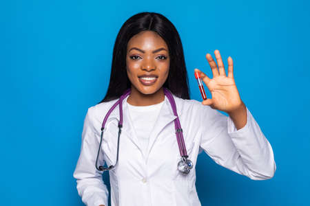 African Doctor holding glass tube with blood on color background, closeup. Allergy test