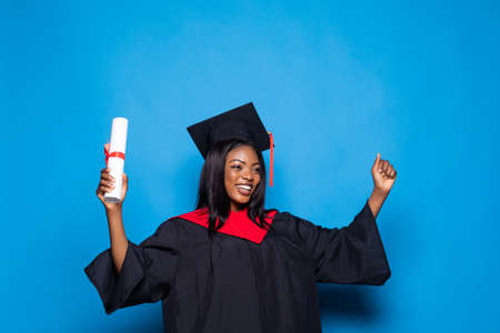 A pretty african american woman graduate isolated on blue backgroundの写真素材