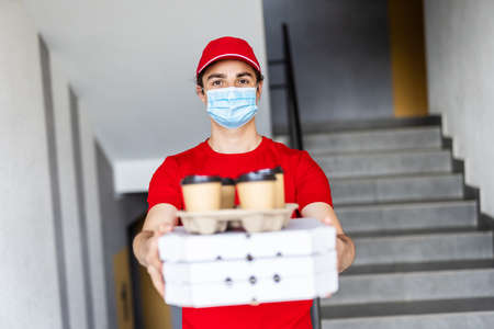 Delivery man holding packages for delivery. Food delivery concept during virus outbreak, covid-19. Stay safe.の写真素材