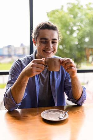 Young man drinking a coffee at the cafeの写真素材