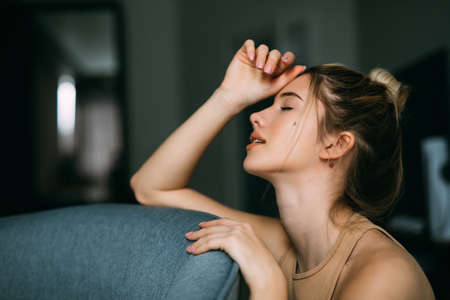 Portrait of smiling young woman relaxing on the chair in the living room at home.