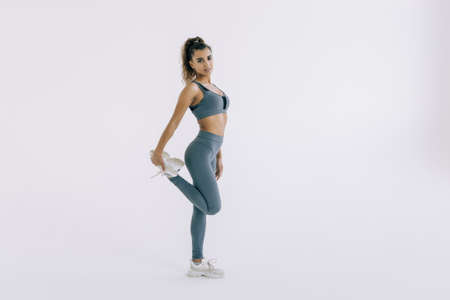 Fitness woman stretching full body. Fitness woman standing stretching thigh in full body on white background.の写真素材