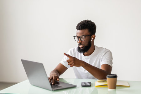 portrait of handsome African black young business man working on laptop computer at office deskの写真素材