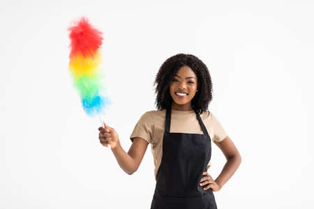 Happy young african housewife holding duster isolated on white backgroundの写真素材