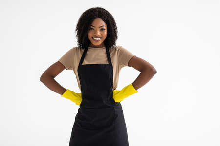 Portrait of young cheerful smiling african woman with rubber gloves cleaning service on white backgroundの写真素材