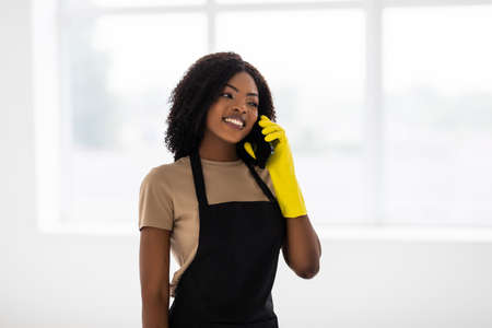 African Woman cleaning home talking on the phone on window backgorundの写真素材