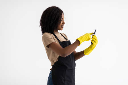 Young african woman hausekeeper use phone on white background