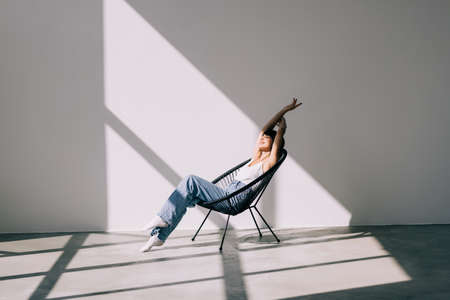 Happy cute pretty woman lying in the armchair on the weekend.の写真素材