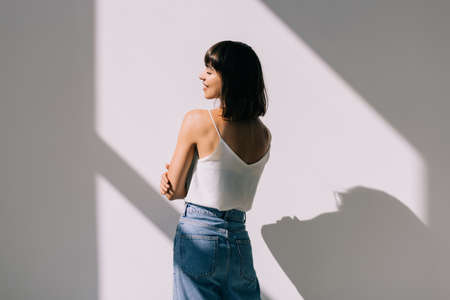 Young woman holds her hand over the sun rays iolated on white backgroundの写真素材