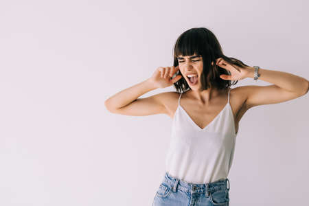 young woman covering her ears isolated on whiteの写真素材
