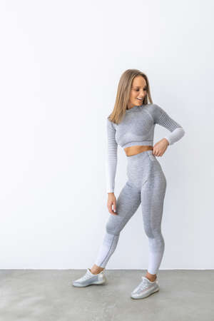 Full body of young cheerful smiling woman in sports wear, isolated over white backgroundの写真素材