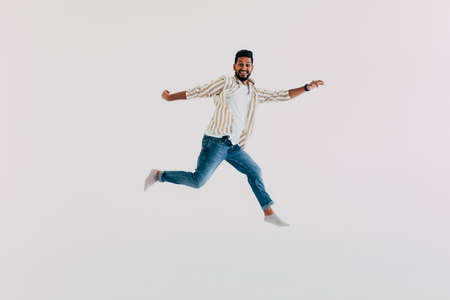 Handsome indian man jumping on white background