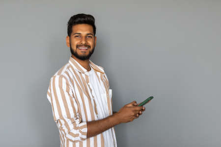 Portrait of indian young man using cellphone on white backgroundの写真素材
