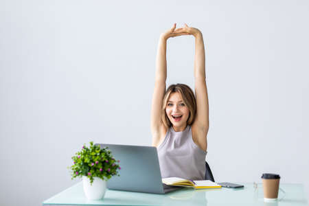 Young woman stretching at her workplace in the officeの写真素材