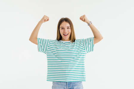 Young attractive woman shouting while her team win, raised both fist in victory gesture, isolated on...