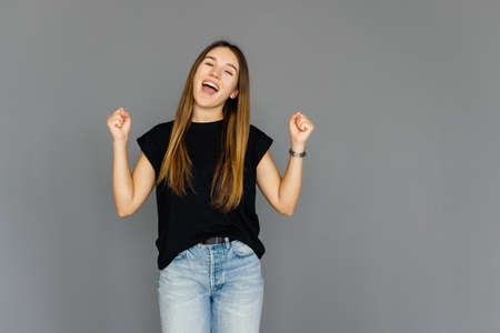 Young attractive woman shouting while her team win, raised both fist in victory gesture, isolated on gray background. Soccer fan conceptの写真素材