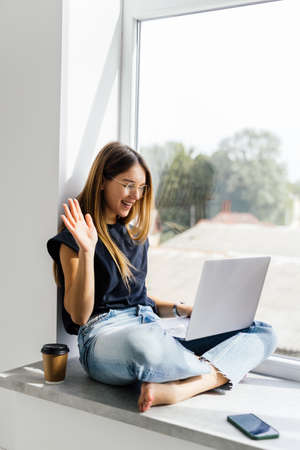 Young pretty woman have video call on laptop from home office Workplace on the windowsill. Concept...