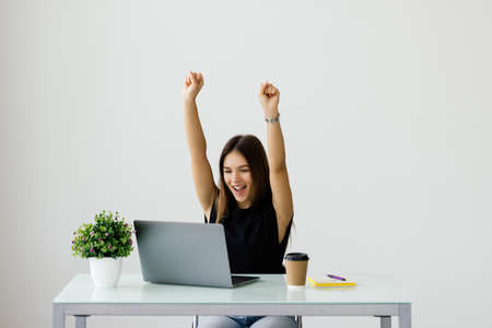 Successful business woman with arms up at the office