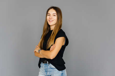 Portrait of a woman in glasses and arms folded over gray background.の写真素材