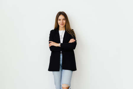 Portrait of beautiful young business woman smiling, standing with arms crossed over white background