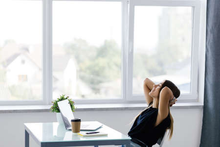 Business woman relaxing with her hands behind her head and sitting on a chairの写真素材