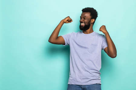Photo of happy young african curly man isolated over green wall background make winner gesture.の写真素材