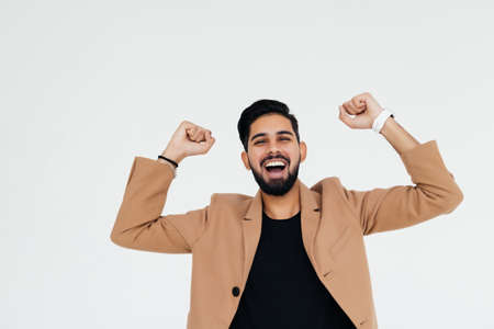 Full length of a successful Indian businessman with clenched fists, celebrating a win. Isolated over white backgroundの写真素材