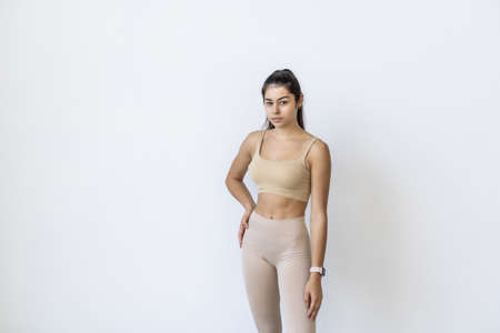 Smiling sports woman standing with arms folded and looking at camera isolated on a white background