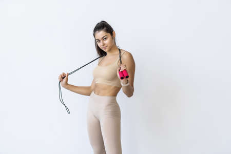Young fit woman with skipping rope on white background