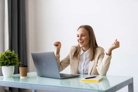 Happy excited successful businesswoman triumphing in officeの写真素材