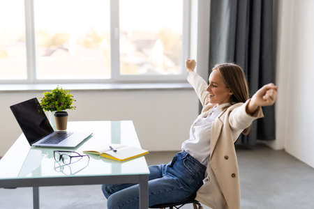 Excited businesswoman celebrating success looking above at officeの写真素材