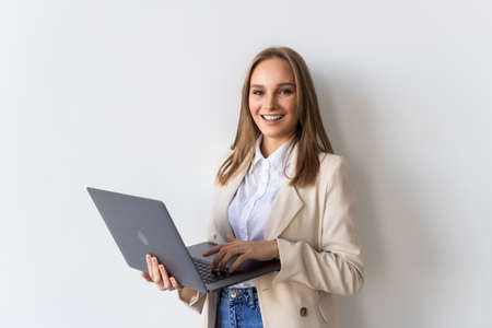Successful young business woman is standing with laptop on white background.