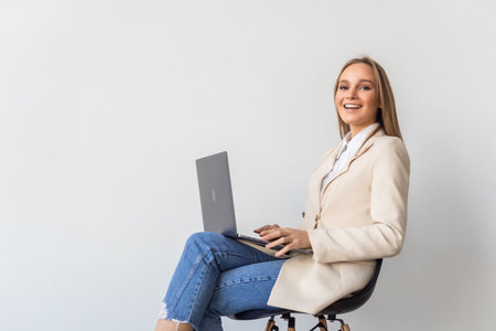 Successful young woman sitting on chair with laptop on isolated on white background.の写真素材