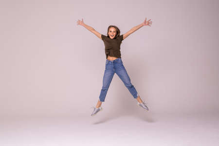 Full length portrait of a cheerful woman jumping isolated on a white backgroundの写真素材