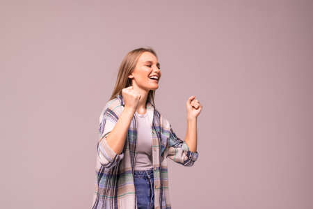 Pretty woman doing a winner gesture happy excited looking up with closed eyes isolated on white backgroundの写真素材