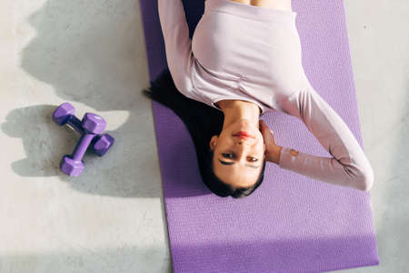 Top view of cute young fitness woman lying on the floor on mat with eyes closedの写真素材